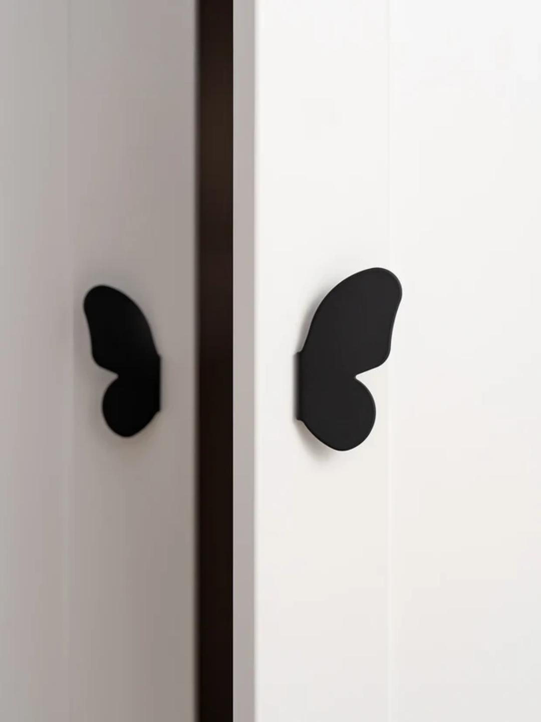Black butterfly-shaped handles on a white cabinet with a black stripe.