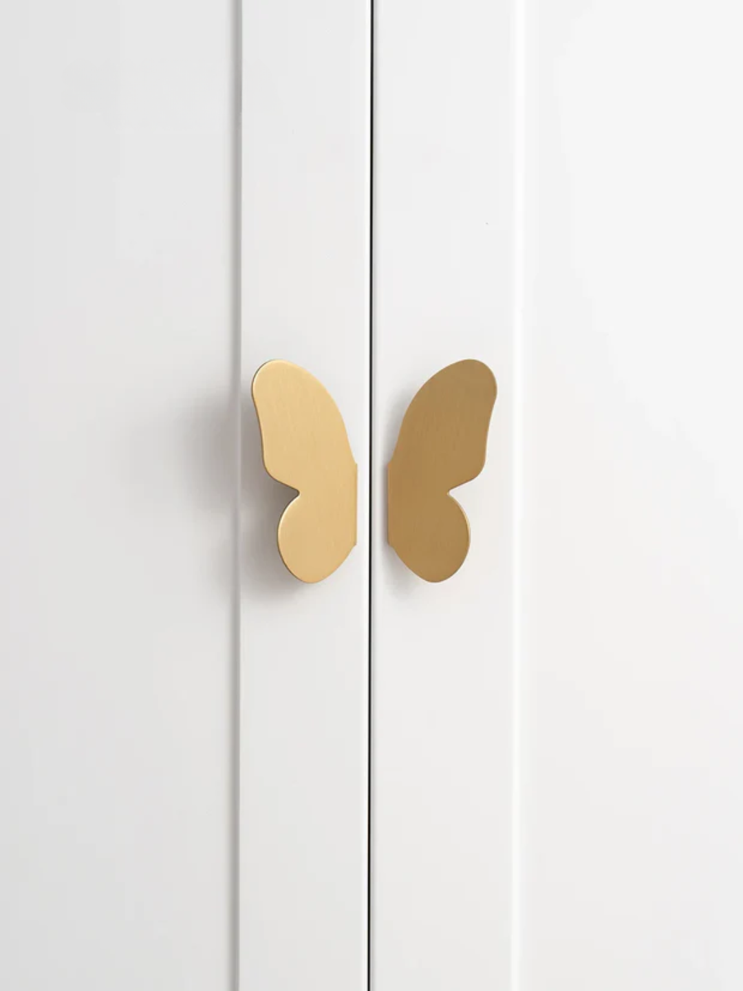 Gold butterfly-shaped cabinet handles on a white cabinet.