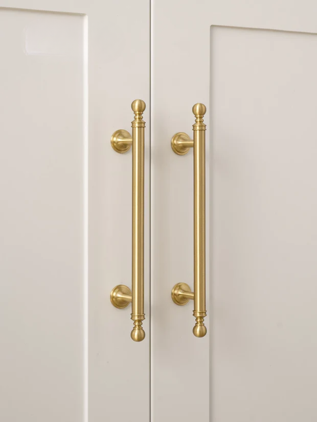 Close-up of gold cabinet handles on a white door