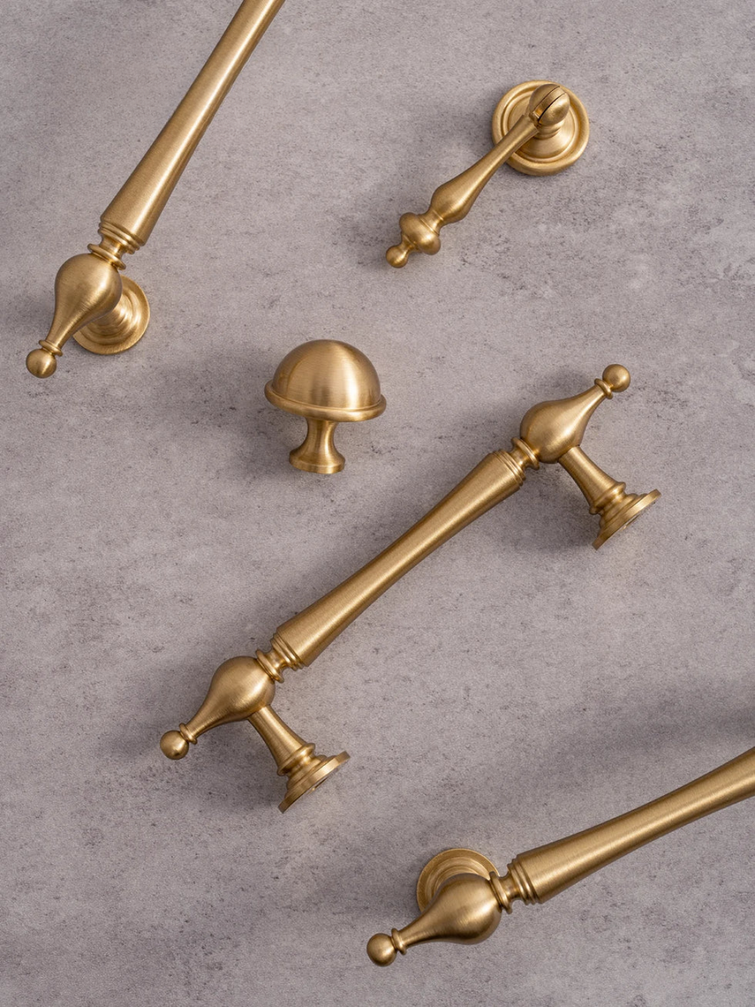 Set of gold cabinet handles and knobs on a gray surface