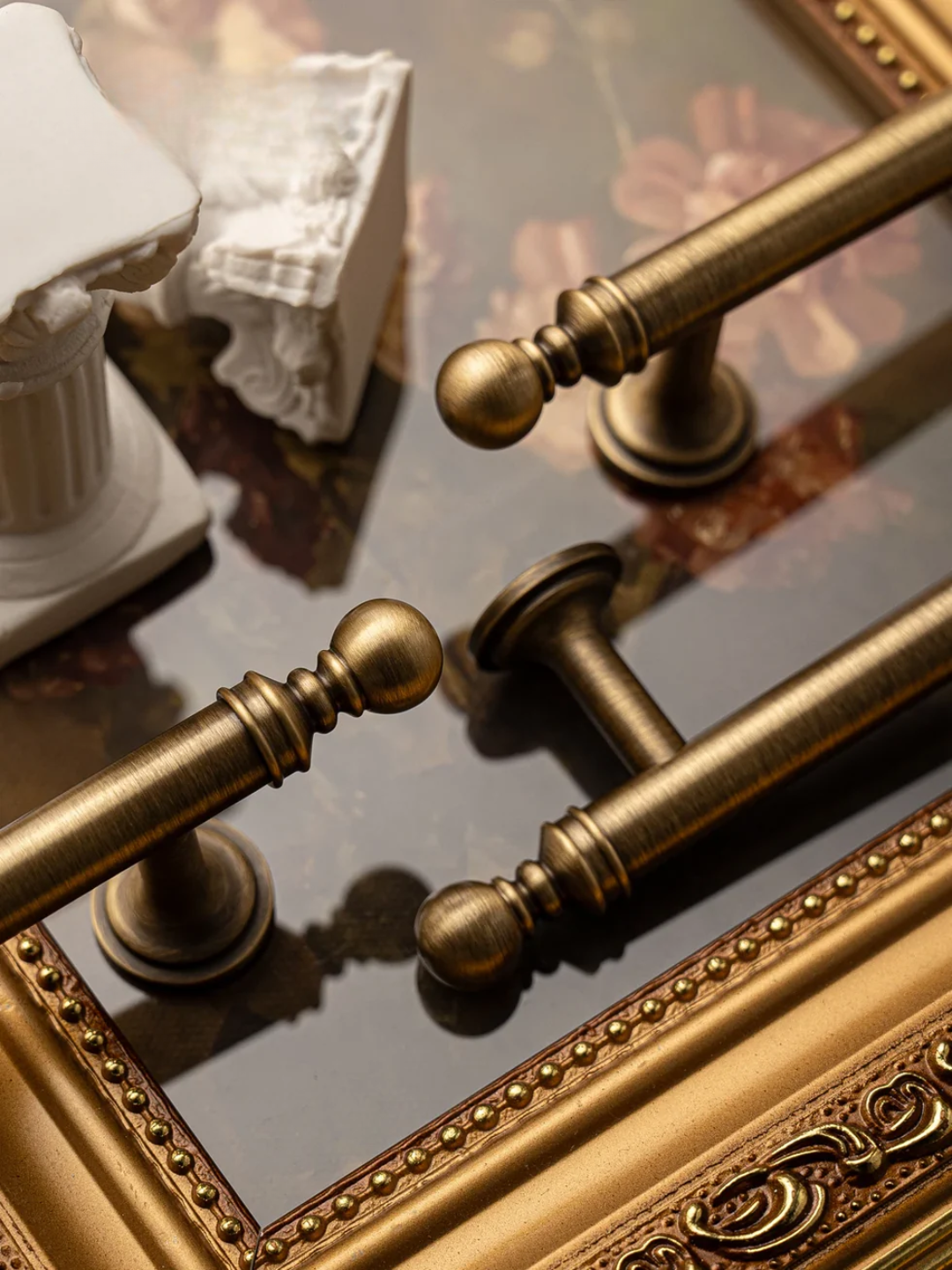 Close-up of ornate gold handles on a reflective surface with decorative elements.