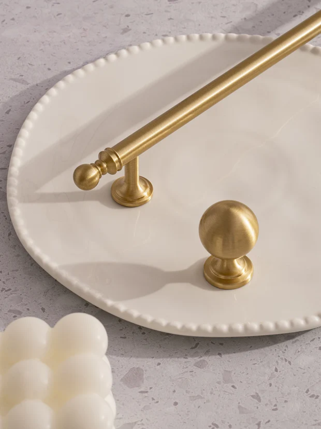 Gold towel bar on a white plate with soap on a gray surface