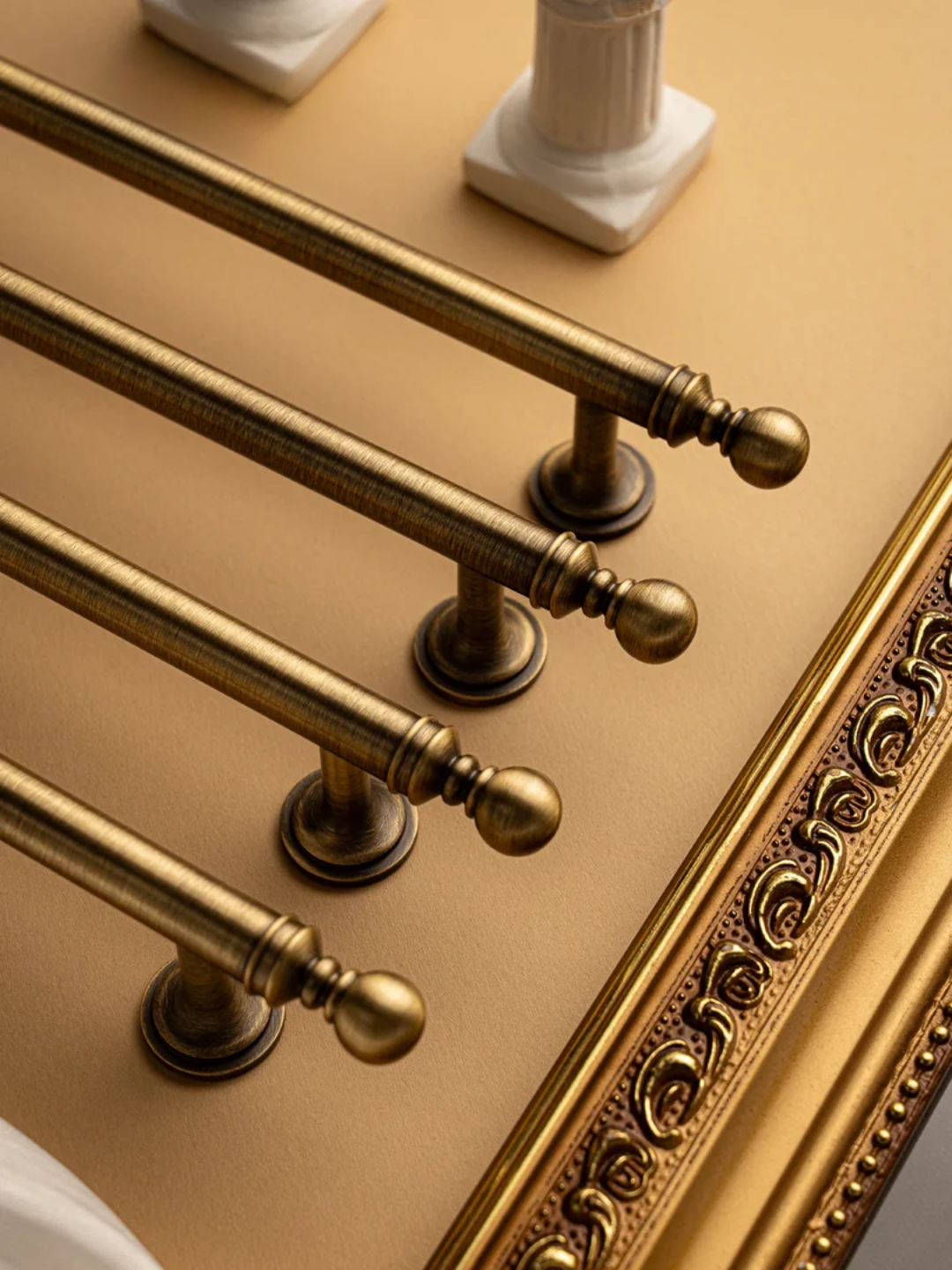 Gold towel rack on a beige wall with decorative elements