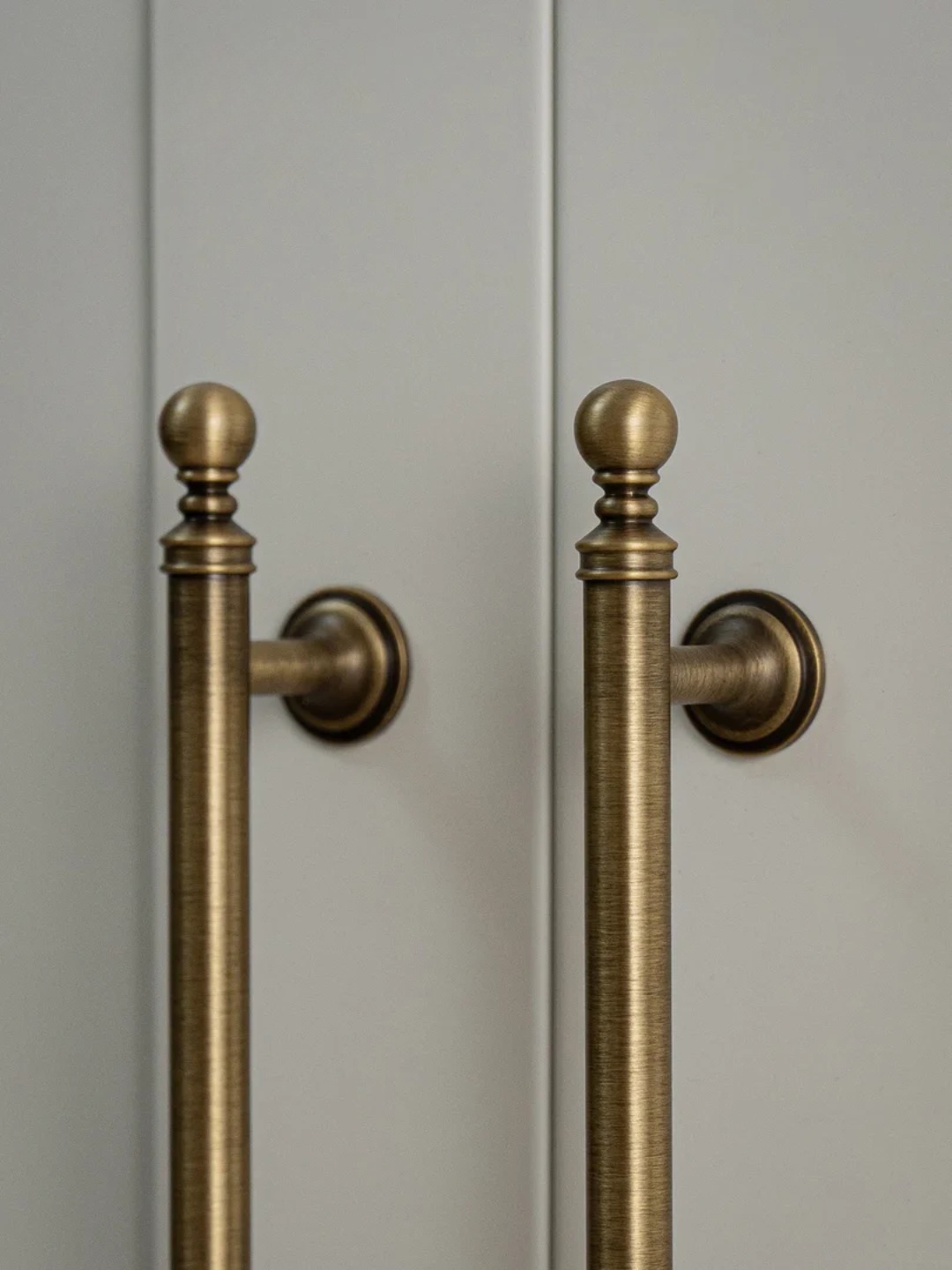 Close-up of bronze door handles on a light gray door