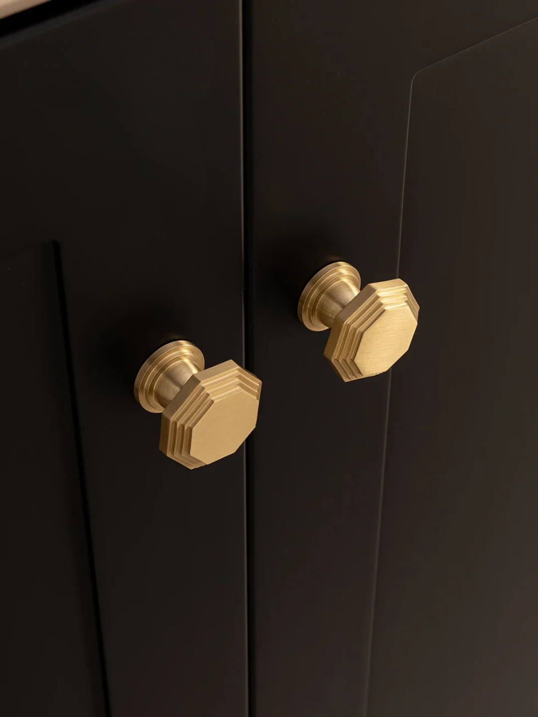 Black cabinet with gold knobs on a dark background