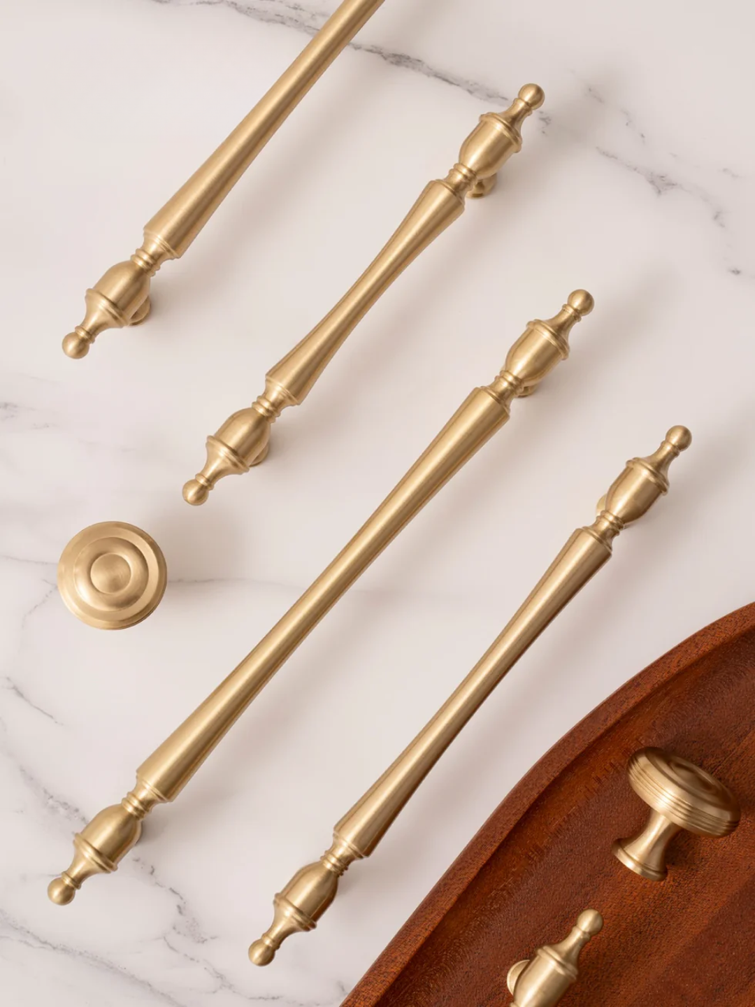 Collection of gold cabinet handles and knobs on a marble surface