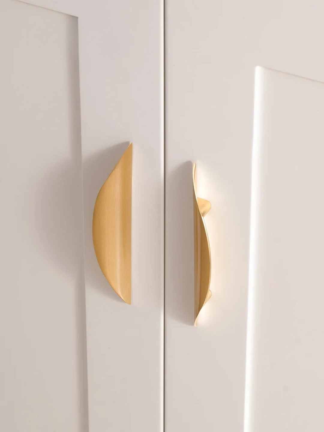 Close-up of a white cabinet with gold handles on a light background