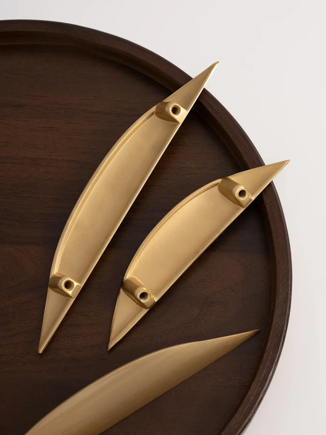 Three gold door handles on a wooden surface