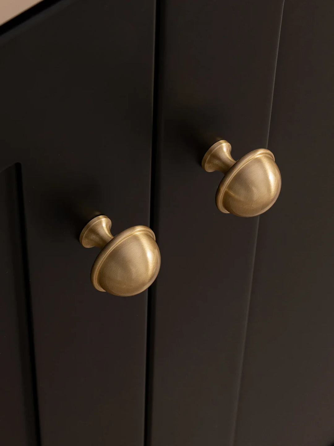 Black cabinet with gold knobs on a dark background