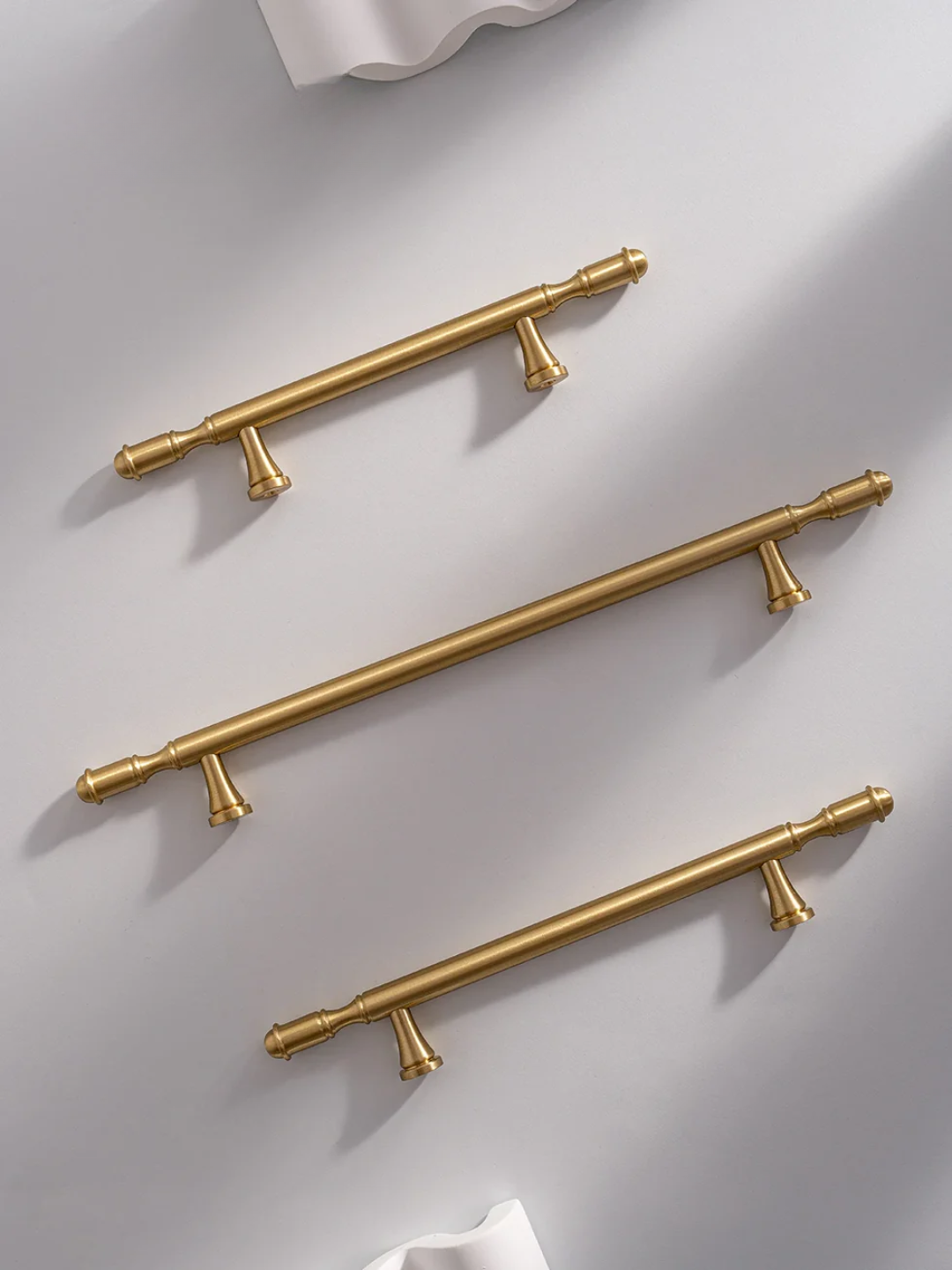 Set of gold cabinet handles on a light gray background