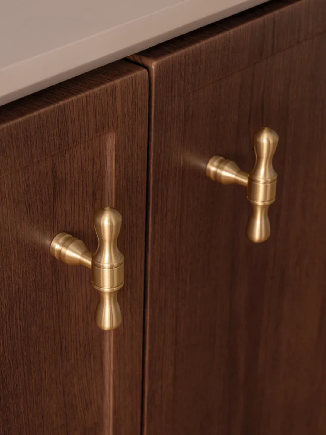 Wooden cabinet with brass handles on a neutral background