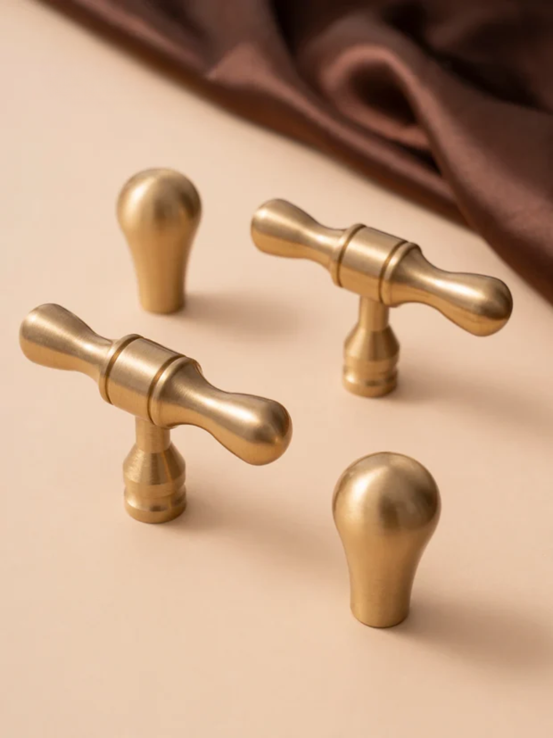 Set of gold cabinet knobs on a beige background