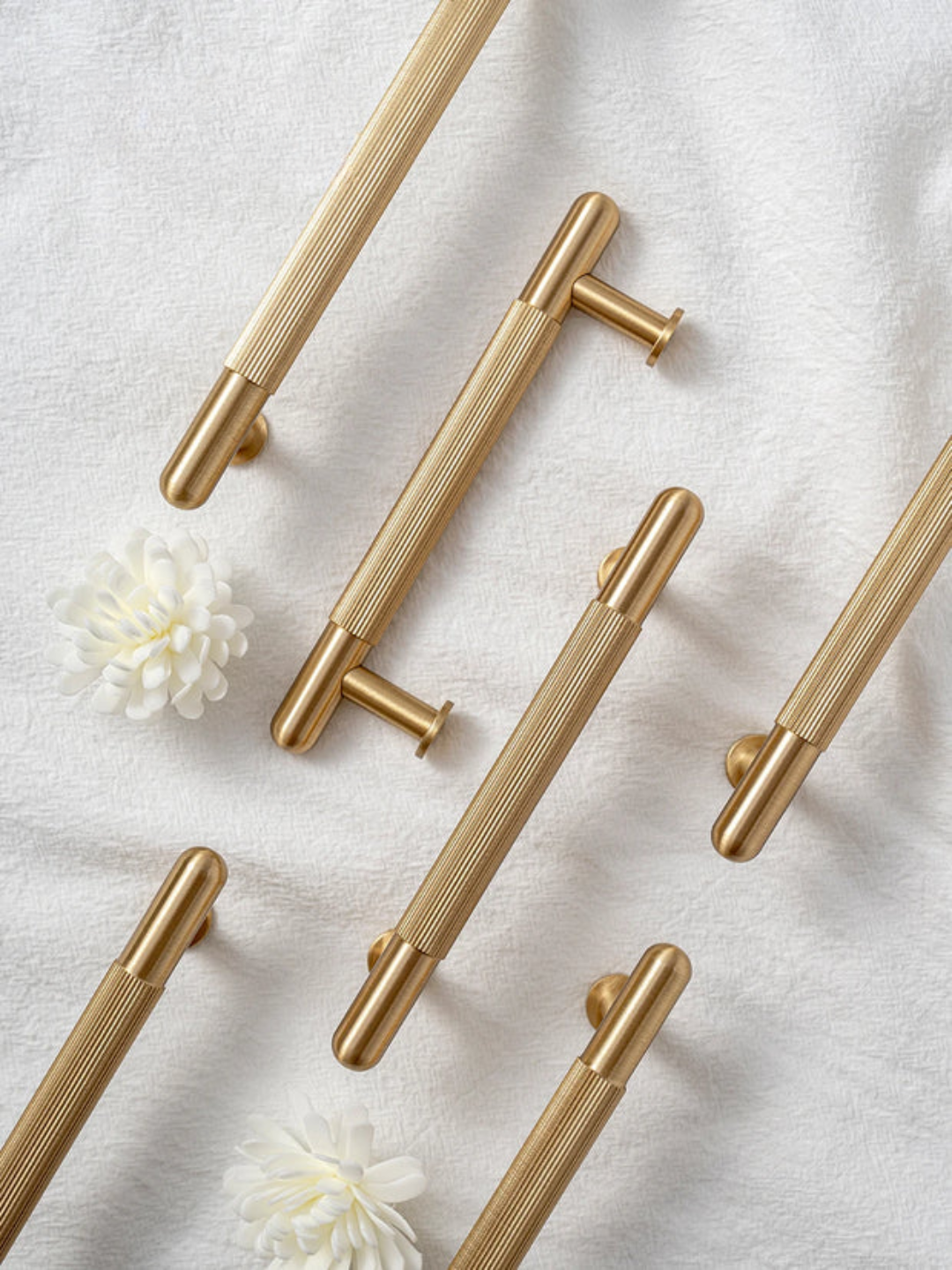 Gold cabinet handles on a light gray background with white flowers.