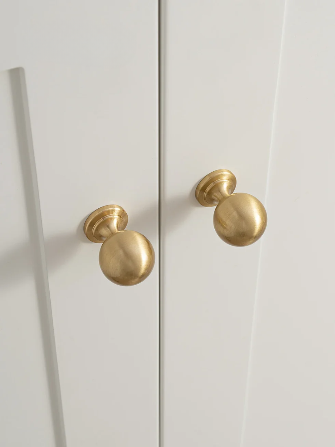 White cabinet with gold knobs on a white background
