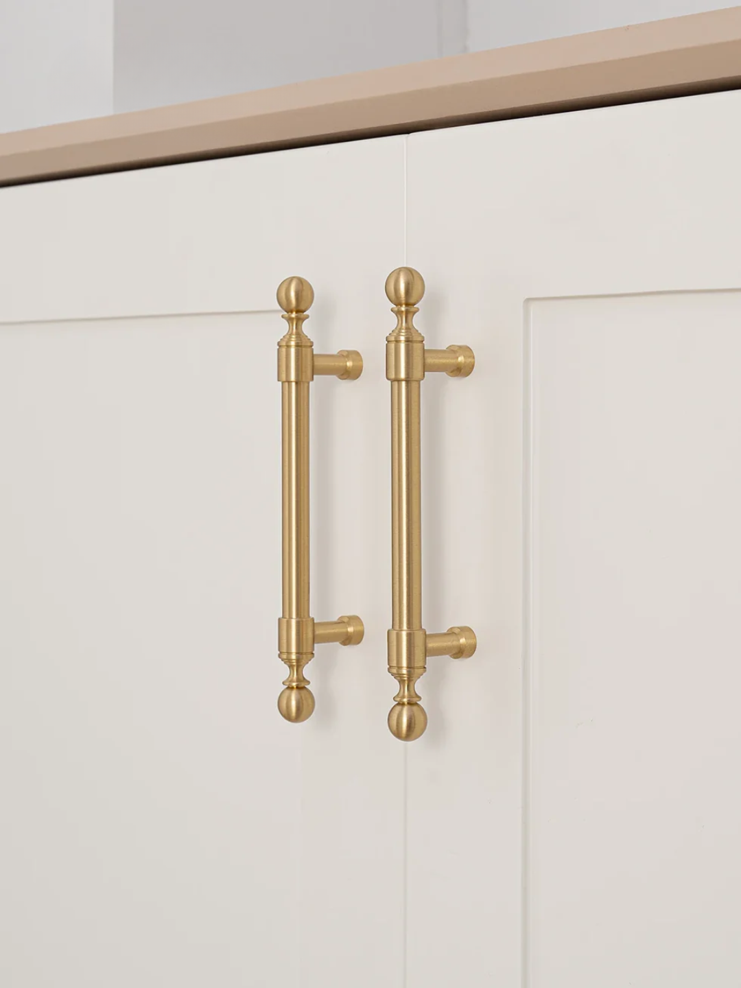 Gold cabinet handles on a white cabinet door