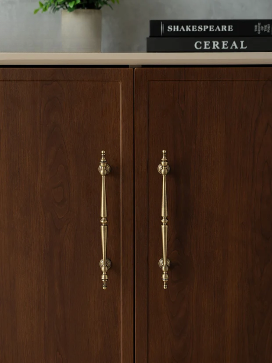 Wooden cabinet with brass handles and 'Shakespeare Cereal' books on top.