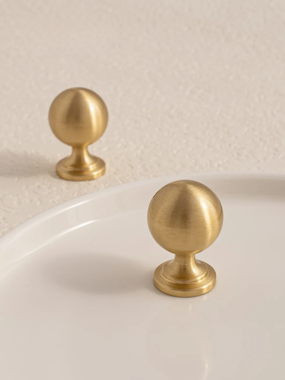 Two gold cabinet knobs on a beige background
