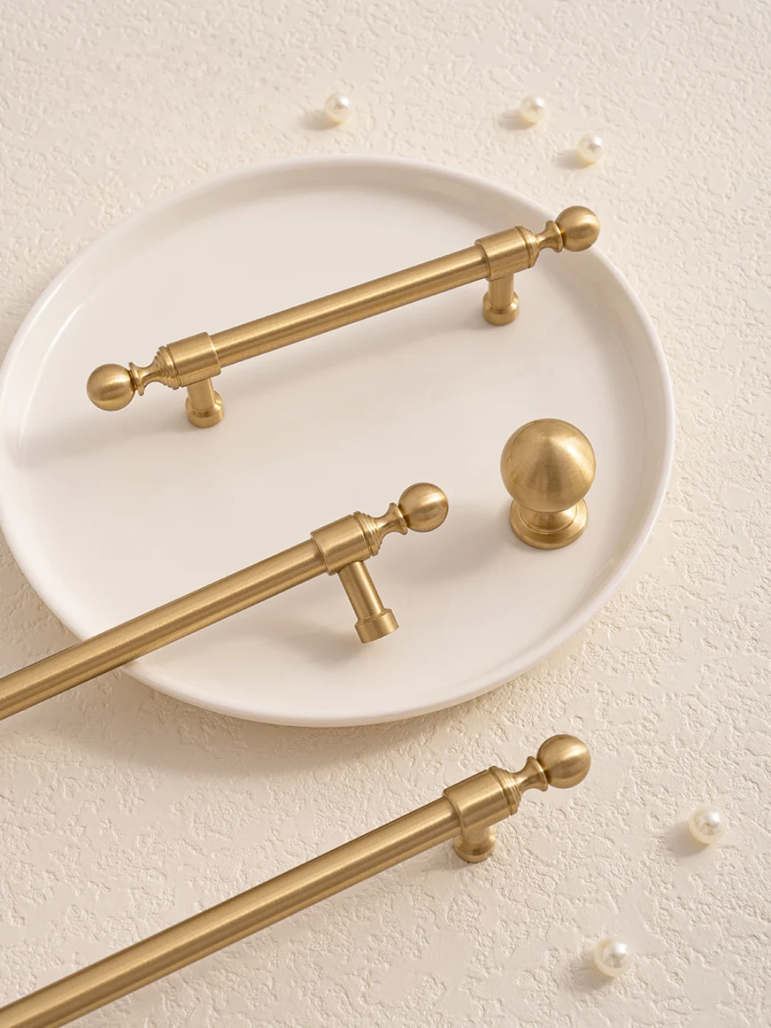 Gold cabinet handles on a beige surface.