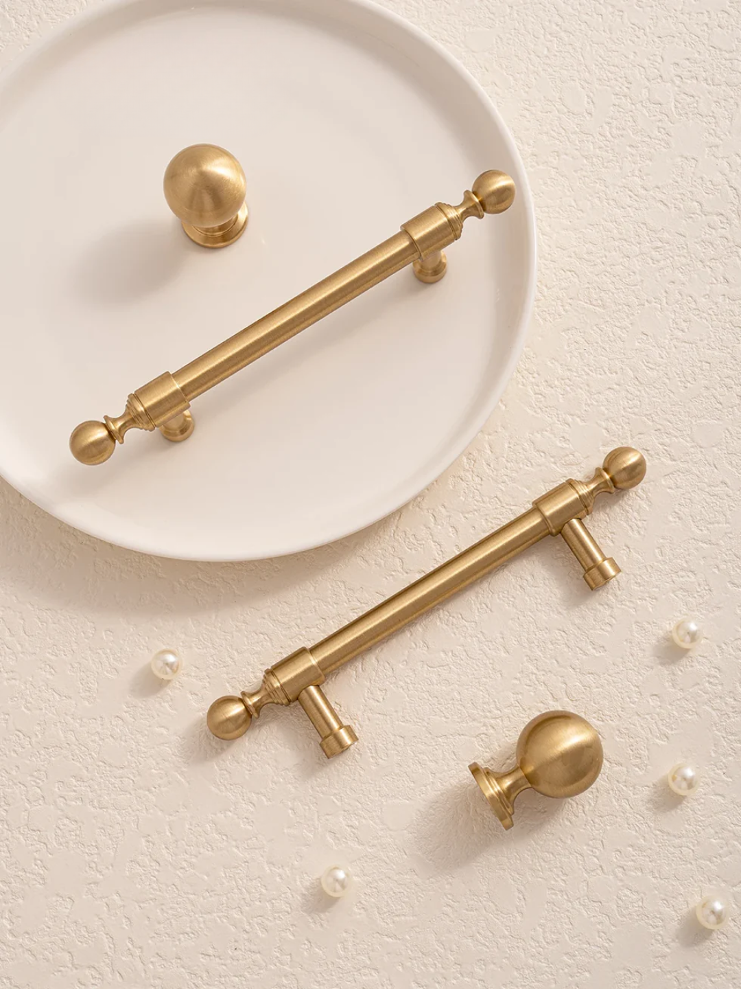 Gold cabinet handles on a beige surface.