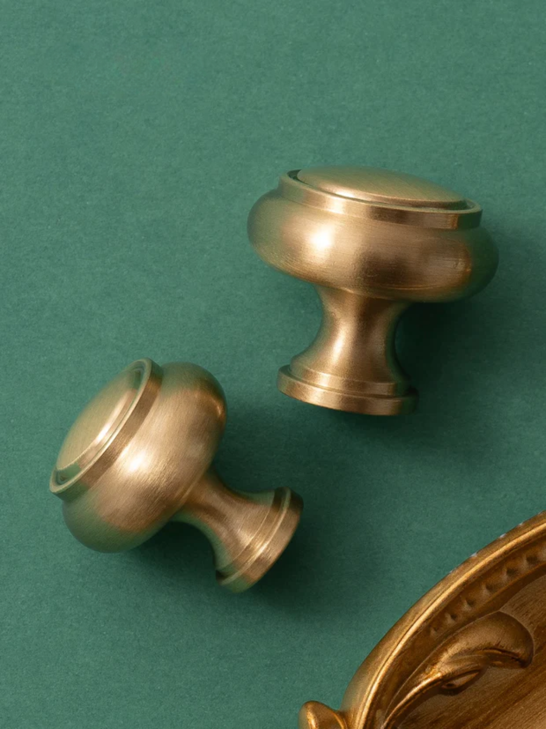Two brass door handles on a green background