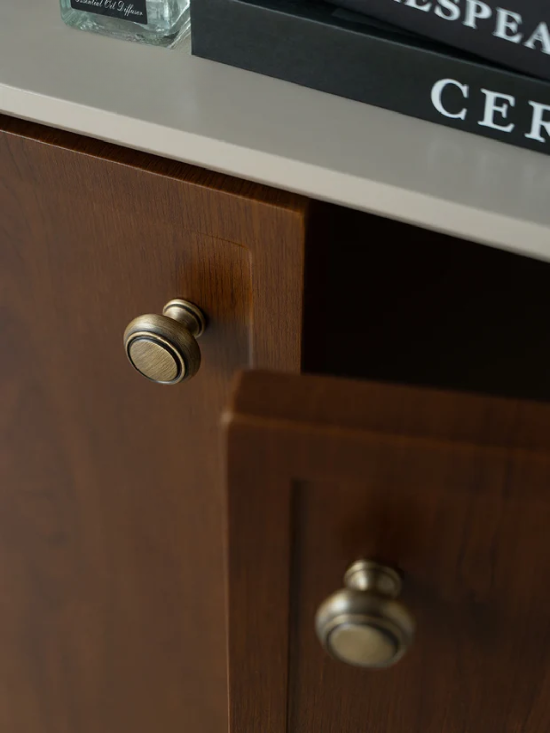 Wooden cabinet with brass knobs on a shelf with a book in the background