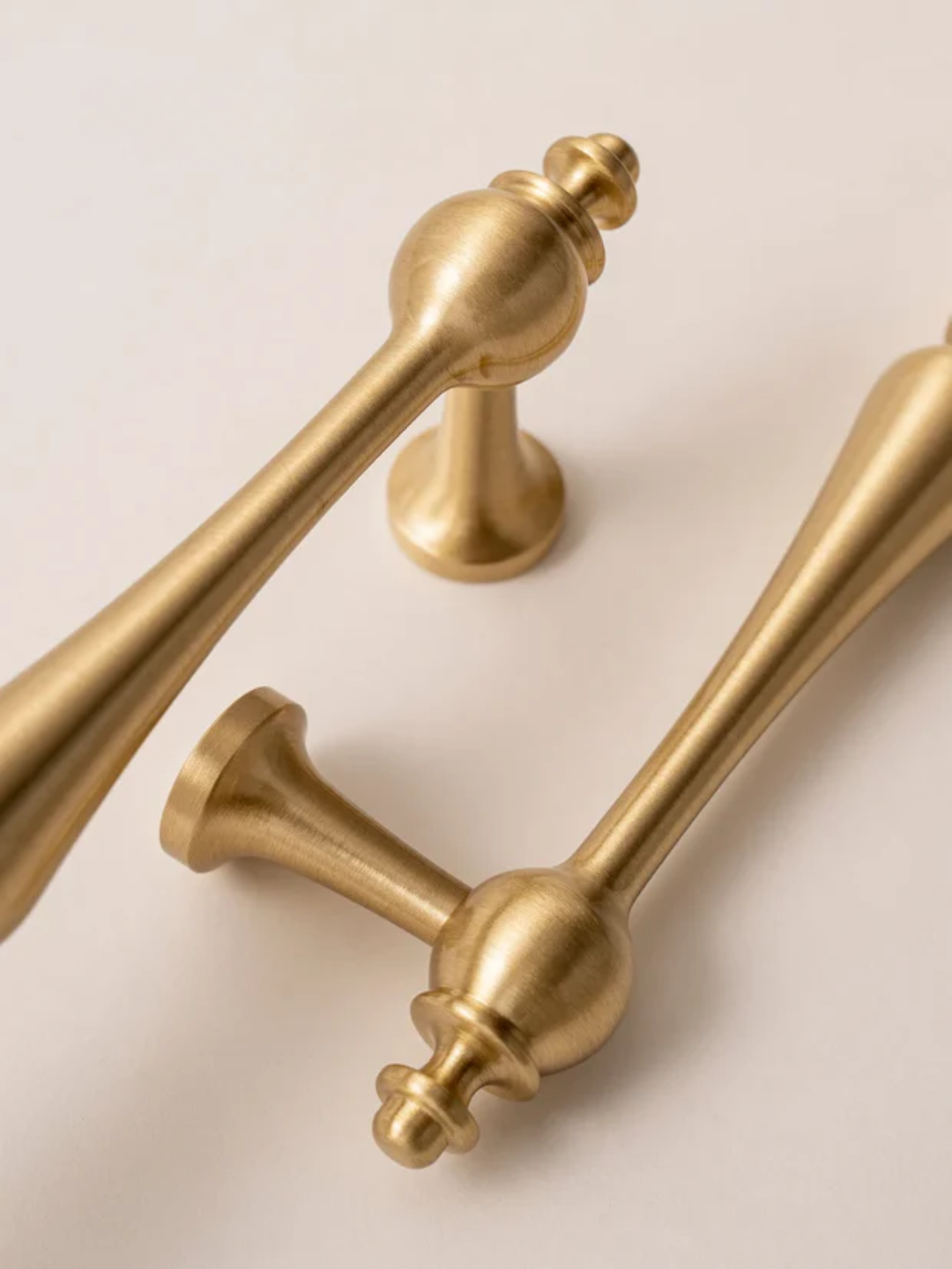 Two gold door handles on a beige background