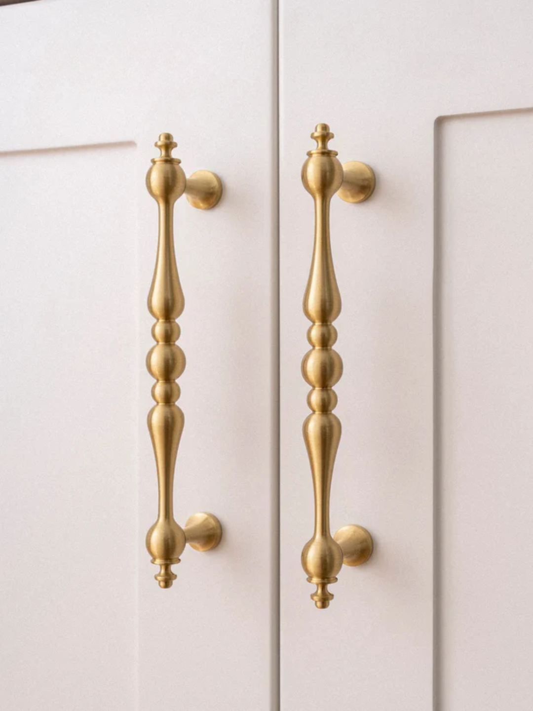 Close-up of gold cabinet handles on a white cabinet door
