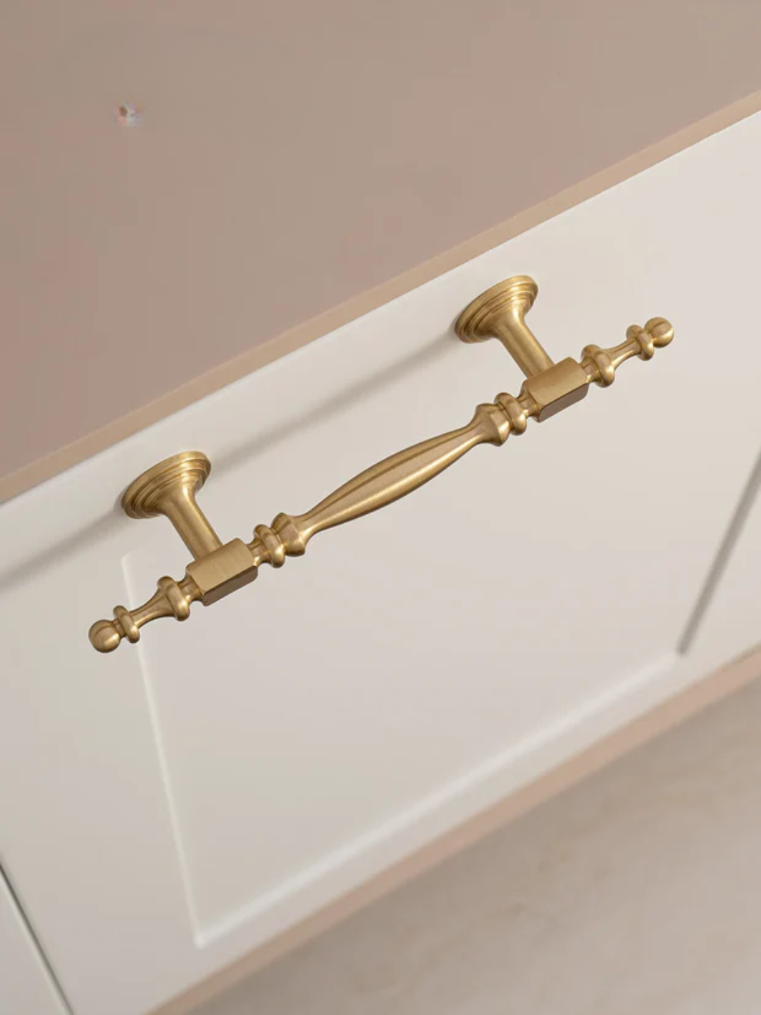 Decorative gold cabinet handle on a white cabinet door.