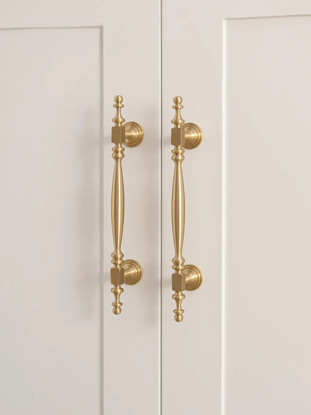 Close-up of a pair of white doors with gold handles on a white background