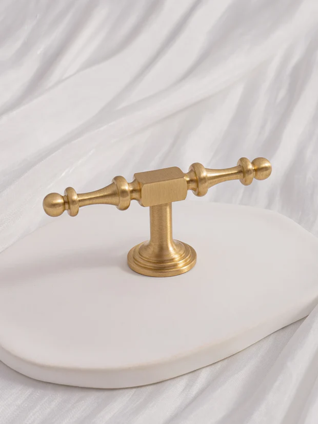 Gold bathroom faucet on a white marble surface with a white curtain background
