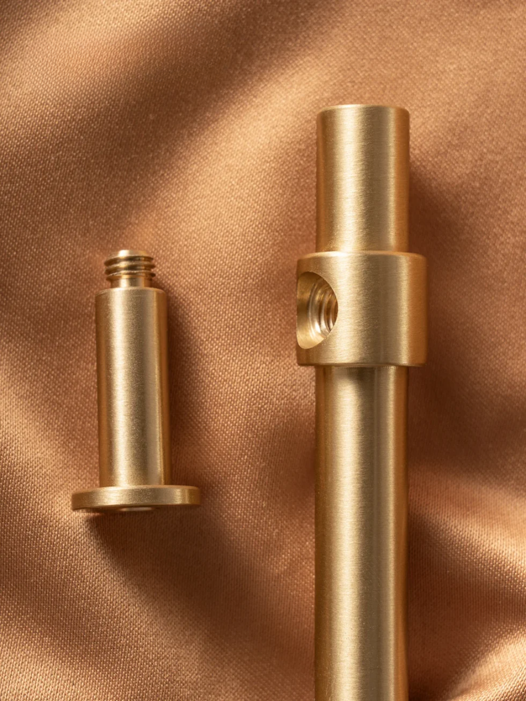 Two brass cylindrical objects on a brown fabric background