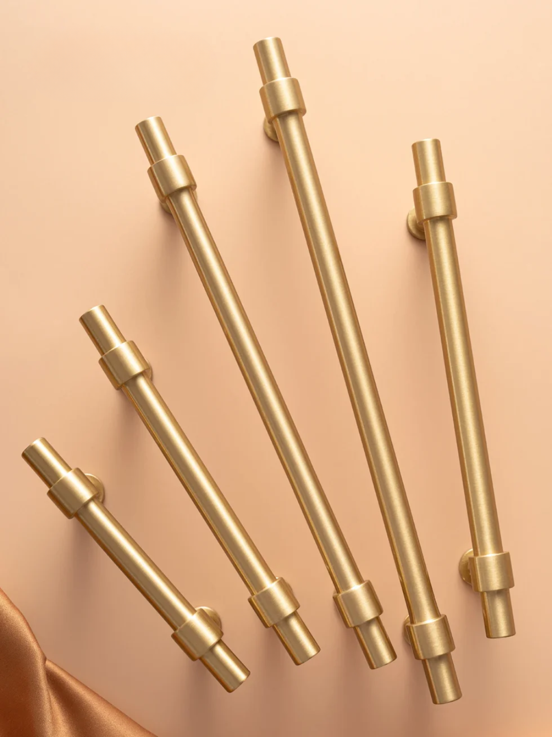 Set of gold cabinet handles on a peach background