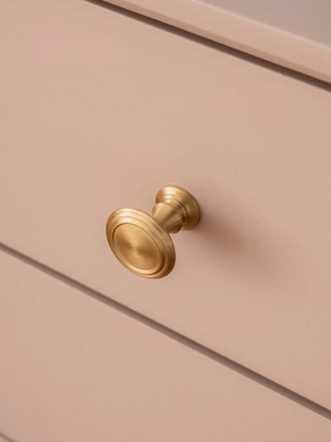 Gold cabinet knob on a beige drawer