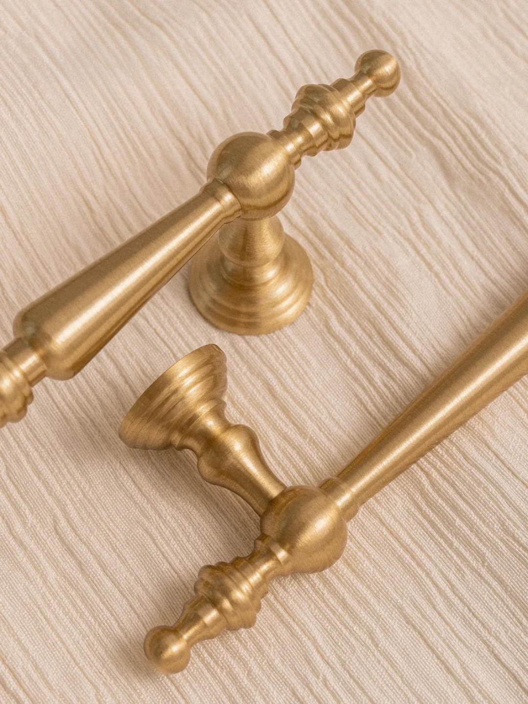 Close-up of ornate gold handles on a textured beige surface