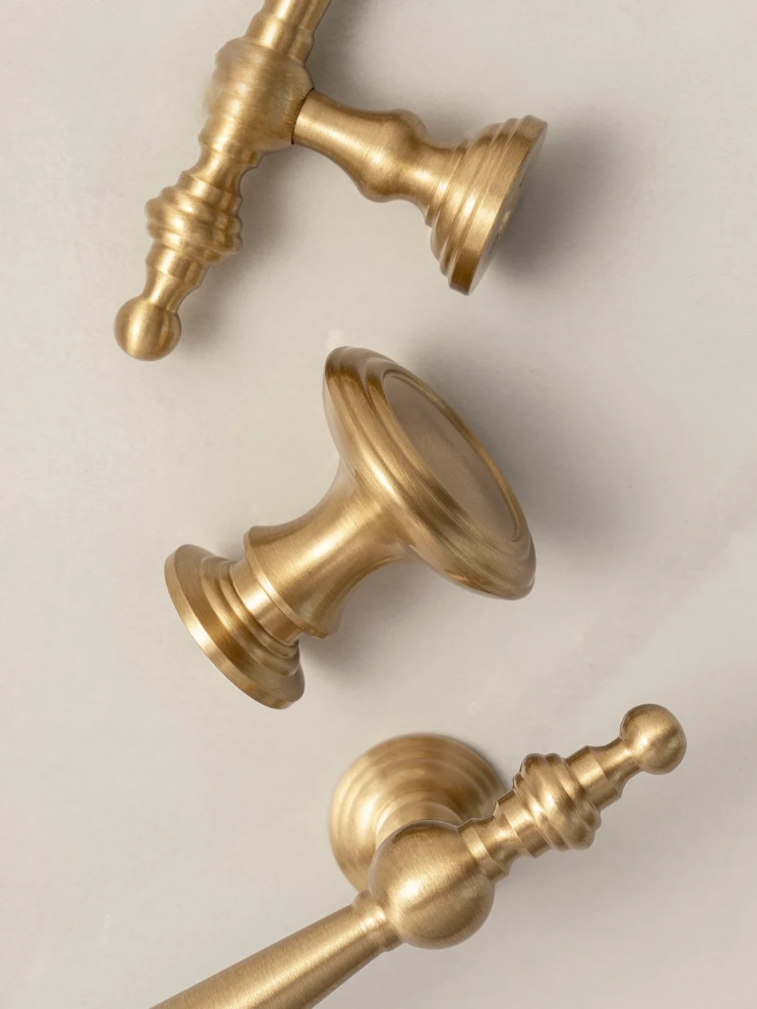 Three gold door handles on a beige background