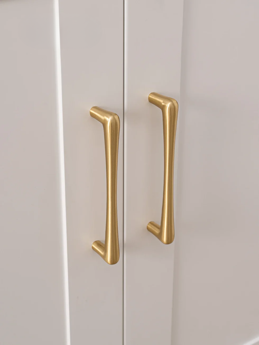 Close-up of gold cabinet handles on a white cabinet