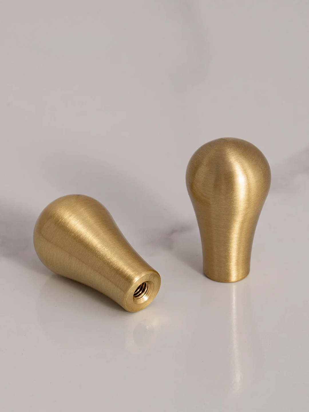 Two brass knobs on a light gray background