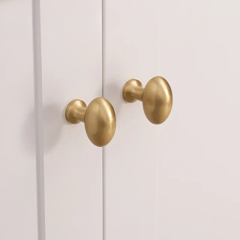 Two gold cabinet knobs on a white door