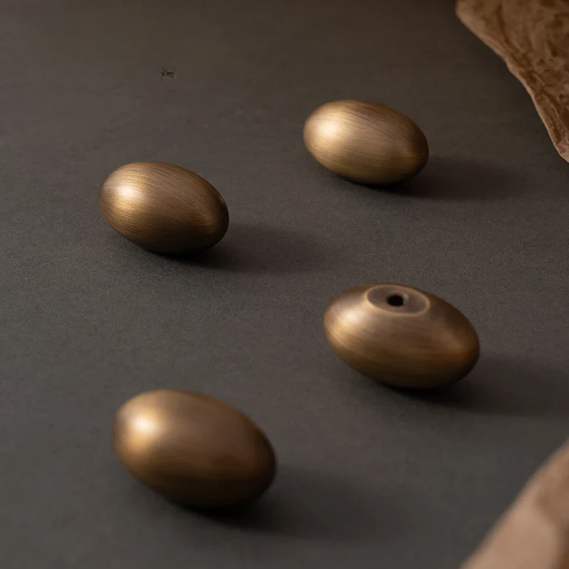 Four bronze-colored beads on a dark surface