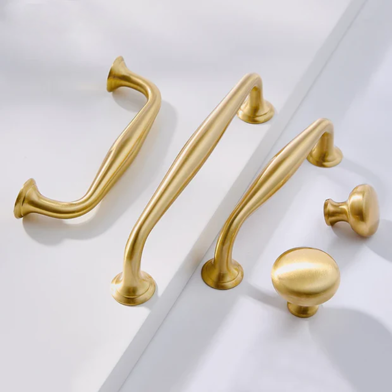 Hand holding a gold door handle on a white door with curtains in the background