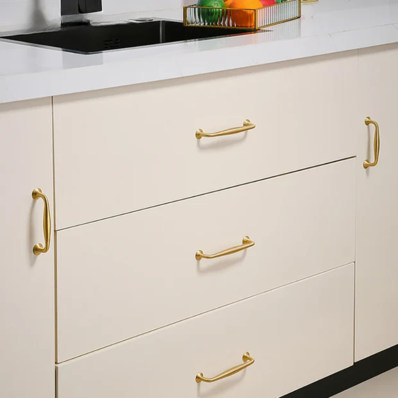 Kitchen cabinets with gold handles on a white countertop.
