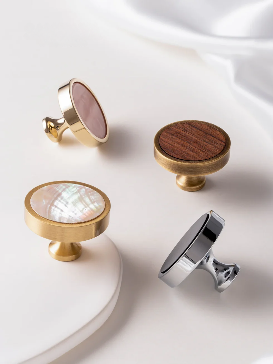 Set of four cabinet knobs with different finishes on a white surface