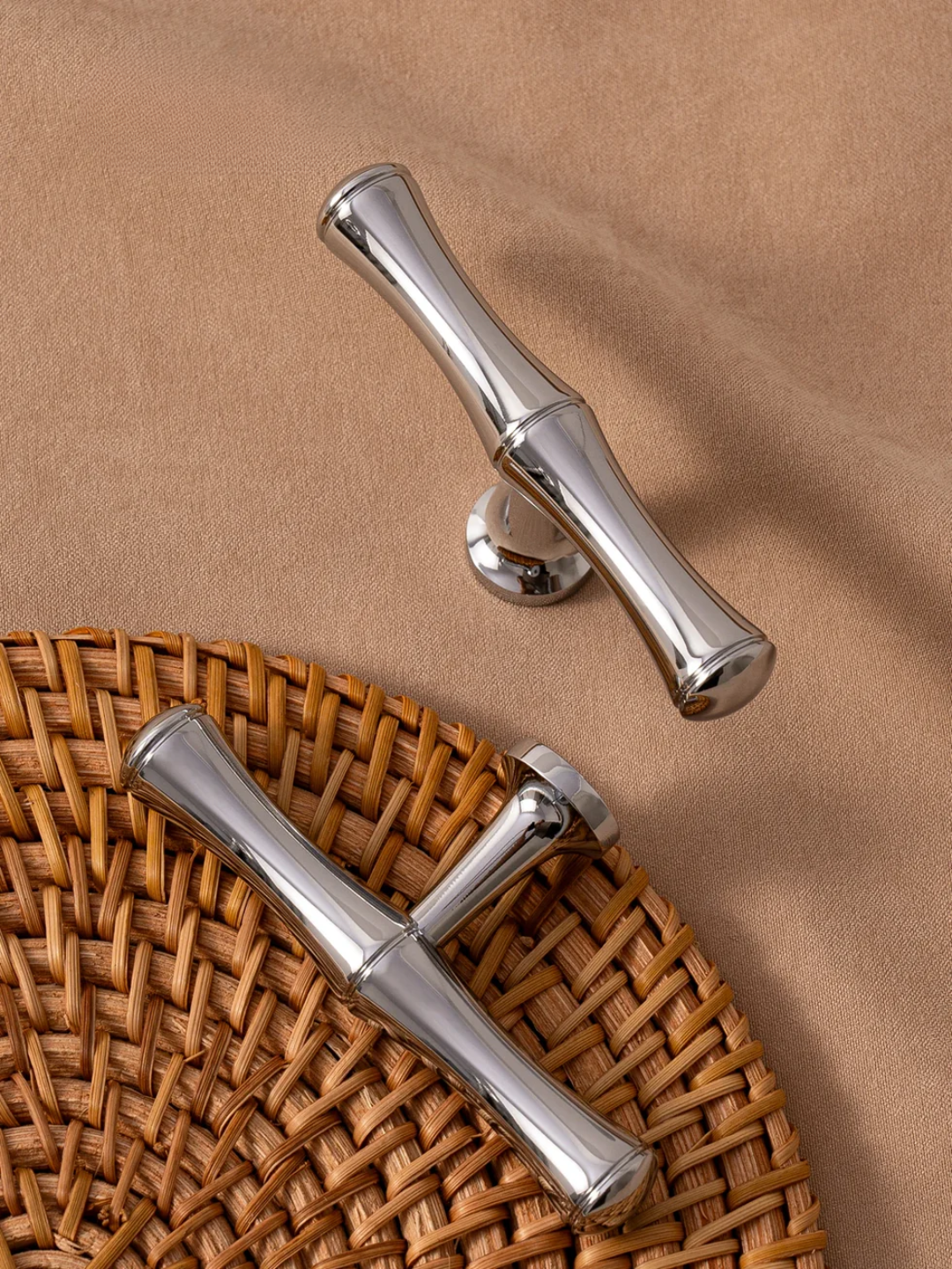 Two silver metal handles on a woven mat with a brown background
