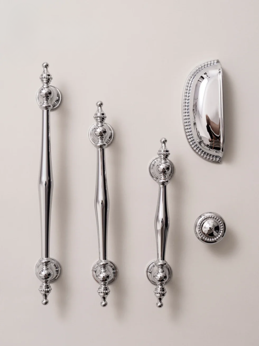 Set of silver door handles and a lock on a beige background