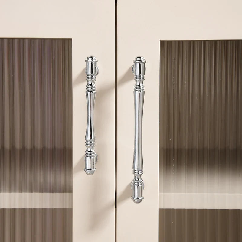 Chrome cabinet handles on a wooden cabinet with a neutral background