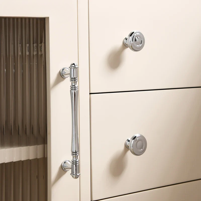 Close-up of a cream-colored cabinet with chrome handles and a blurred background.