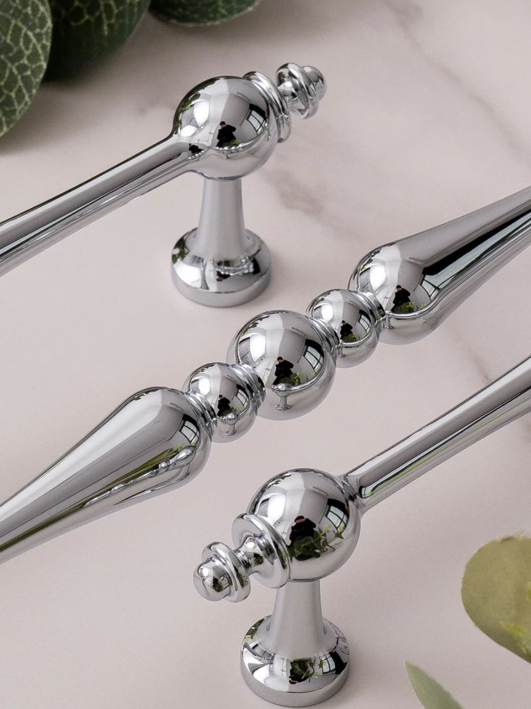 Chrome towel bar set on a light background with green decorative elements.