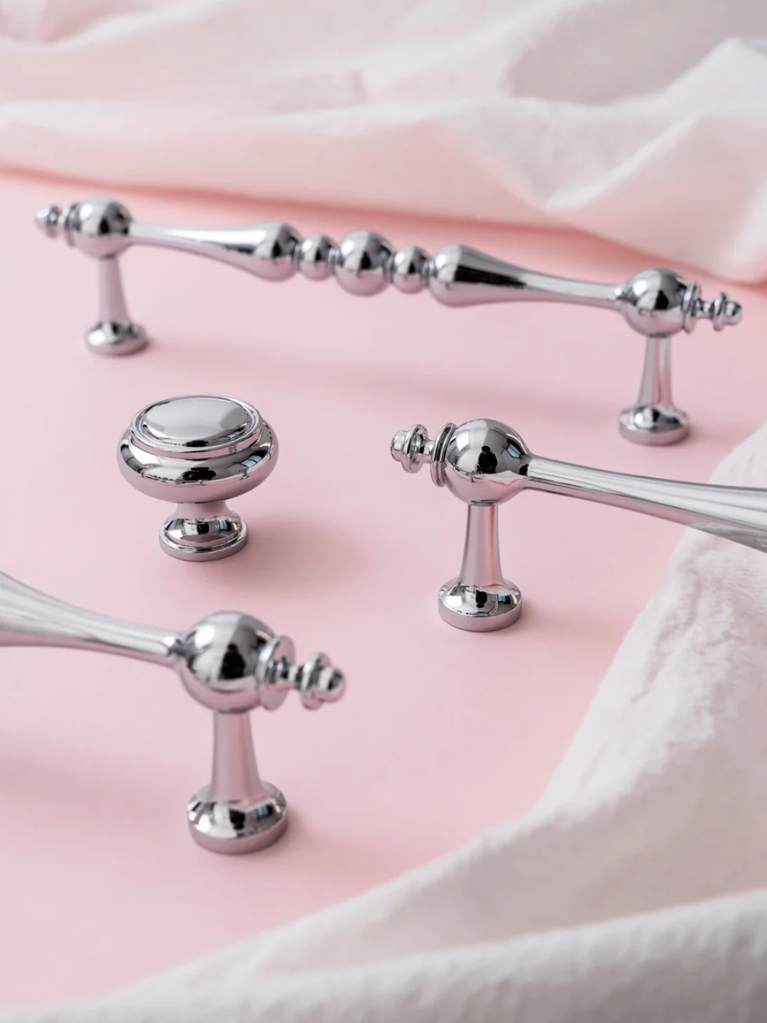 Silver bath accessories on a pink surface