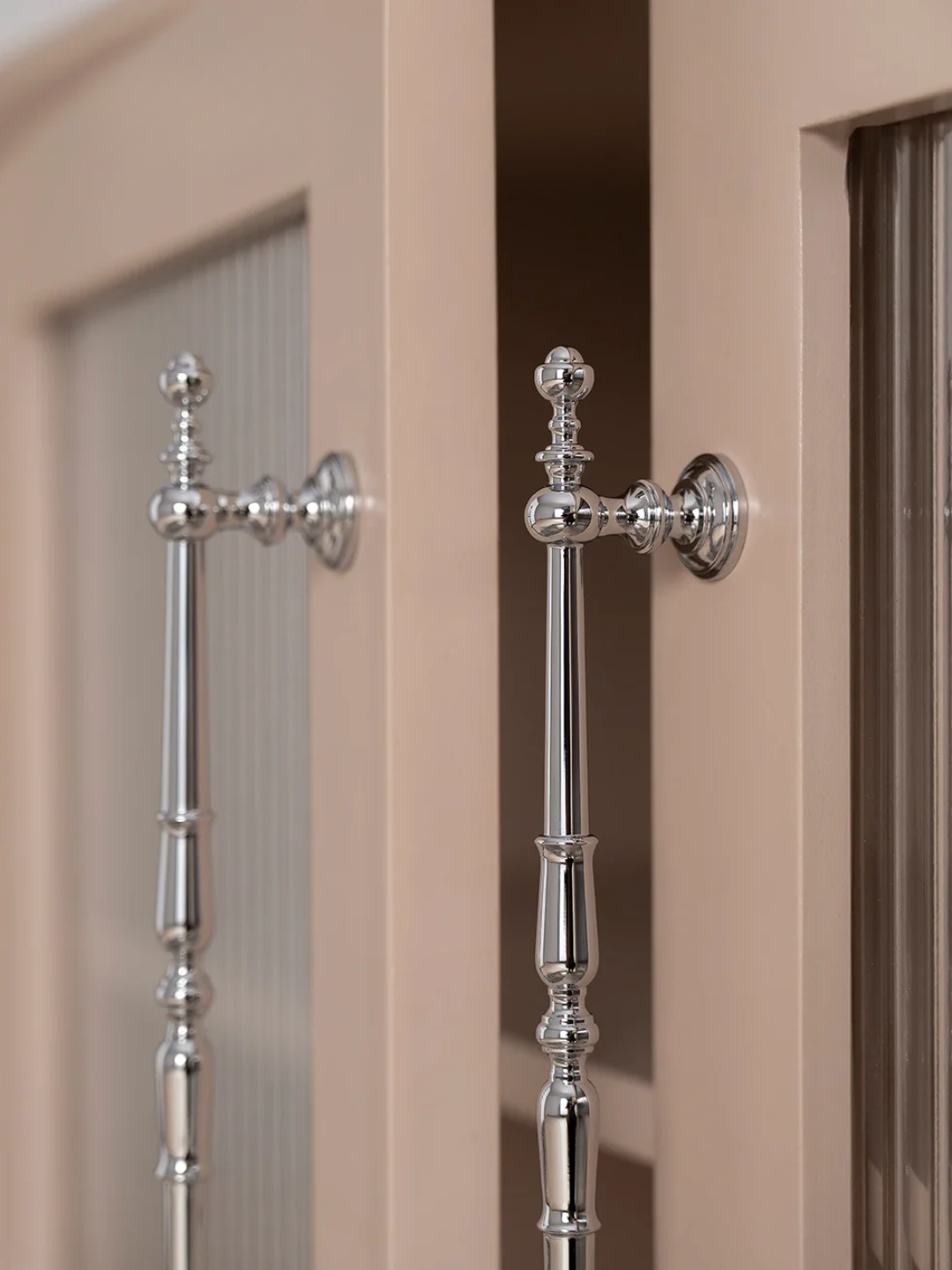 Close-up of decorative silver cabinet handles on a beige cabinet.