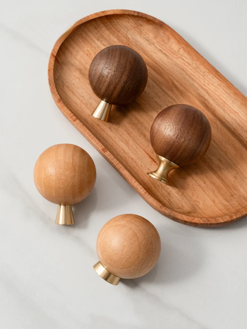 Wooden knobs with gold accents on a wooden tray against a light background